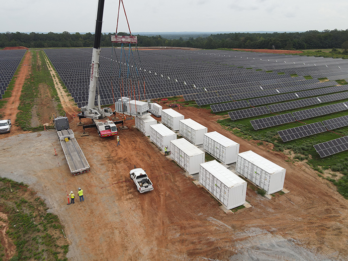 Crane installing battery energy storage containers at a Pure Power solar project
