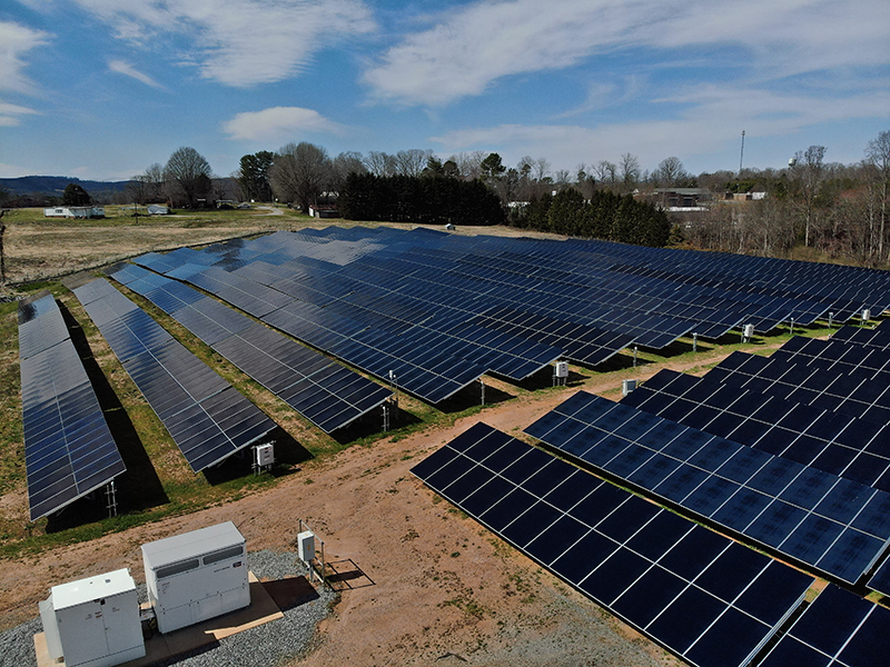 Aerial view of an operational solar farm with combiner boxes and clean panel rows